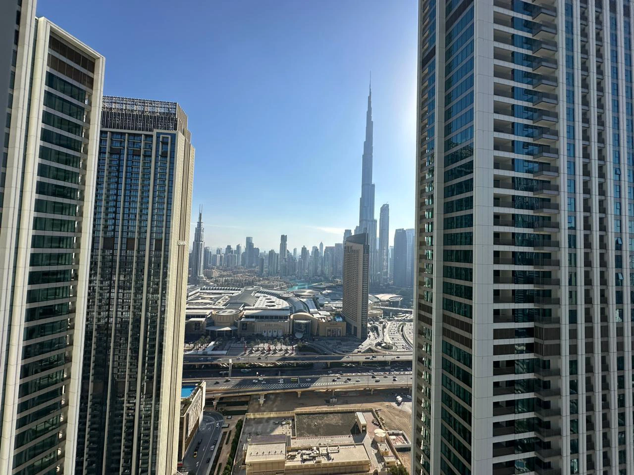 Exterior view of Downtown Views II, a modern apartment complex in Dubai, featuring sleek architectural design with glass facades, and an interior shot of a three-bedroom apartment with contemporary decor, large windows, and luxurious finishes.