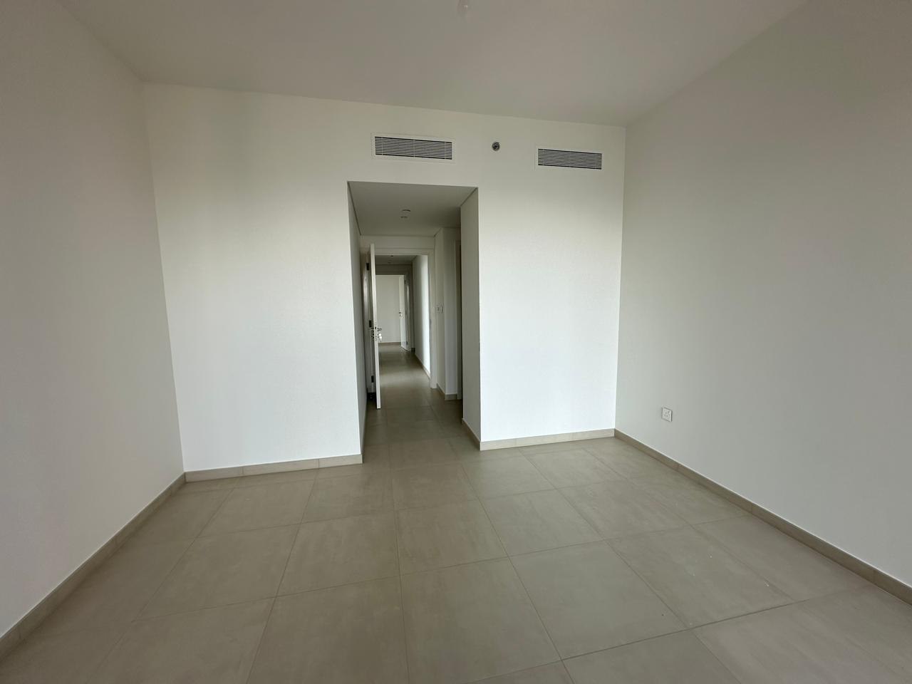 Exterior view of Downtown Views II, a modern apartment complex in Dubai, featuring sleek architectural design with glass facades, and an interior shot of a three-bedroom apartment with contemporary decor, large windows, and luxurious finishes.